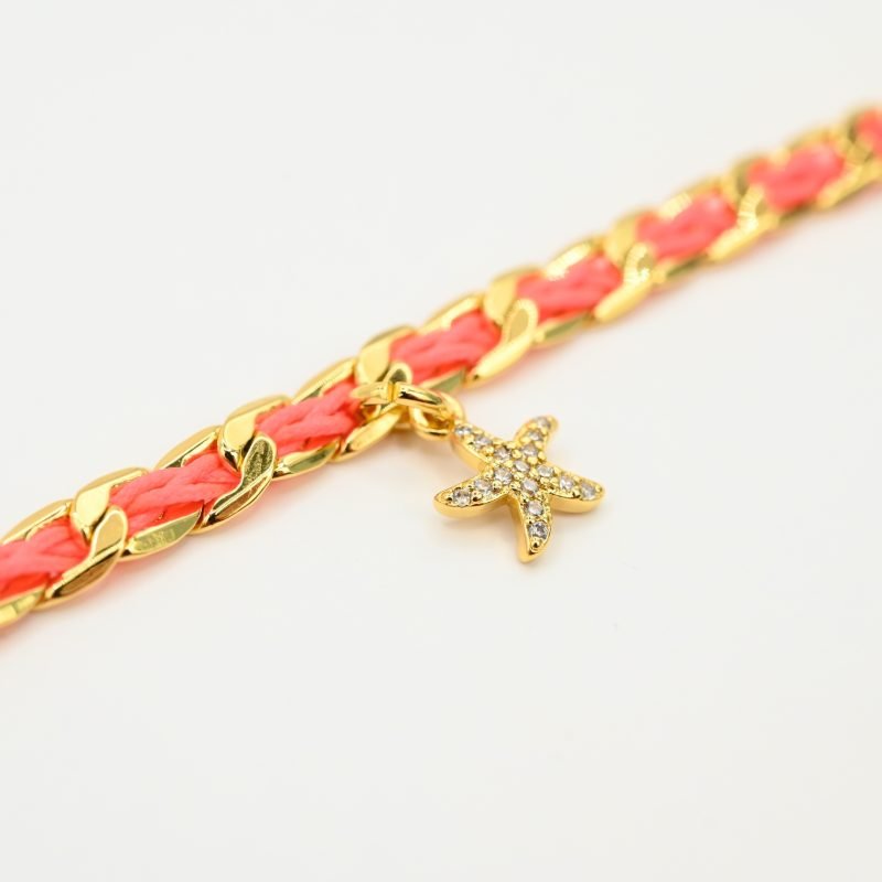 "1 pampille coeur strass Couleur tressage : rose poudré. Fermoir réglable. Matière : plaqué or et incrustation de fils de coton polyester tressés. Utilisation possible sous la douche ! . Bijou seul, Crédit GEMITY"