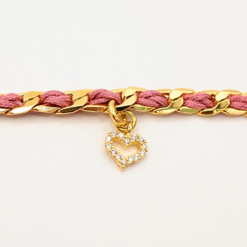 "1 pampille coeur strass Couleur tressage : rose poudré. Fermoir réglable. Matière : plaqué or et incrustation de fils de coton polyester tressés. Utilisation possible sous la douche ! . Bijou seul, Crédit GEMITY"